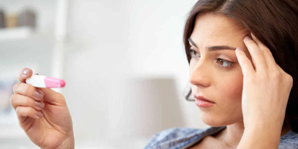 pregnancy, fertility, maternity and people concept - sad unhappy woman looking at pregnancy test at home pregnancy, fertility, maternity and people concept - sad unhappy woman looking at pregnancy test at home