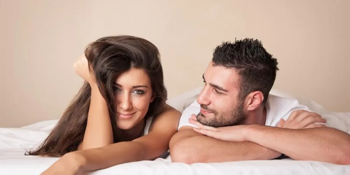 portrait de jeune couple heureux se détendre dans la chambre d'hôtel tout en s'allongeant sur le lit