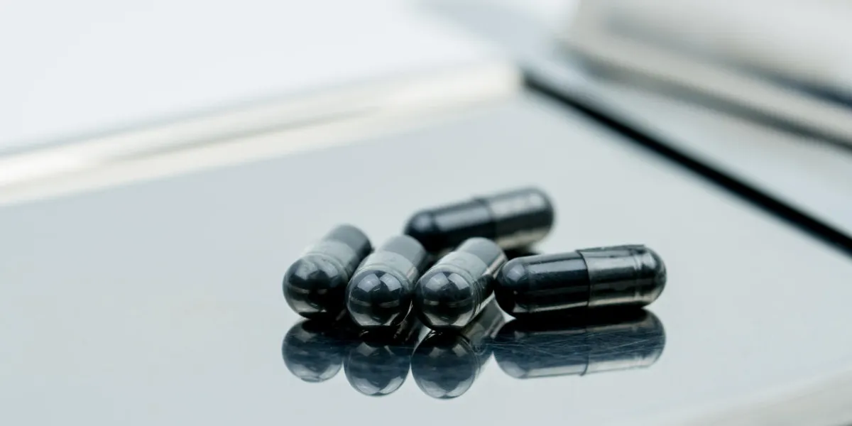selective focus on powders of activated charcoal on stainless steel drug tray and blur capsule background selective focus on powders of activated charcoal on stainless steel drug tray and blur capsule background