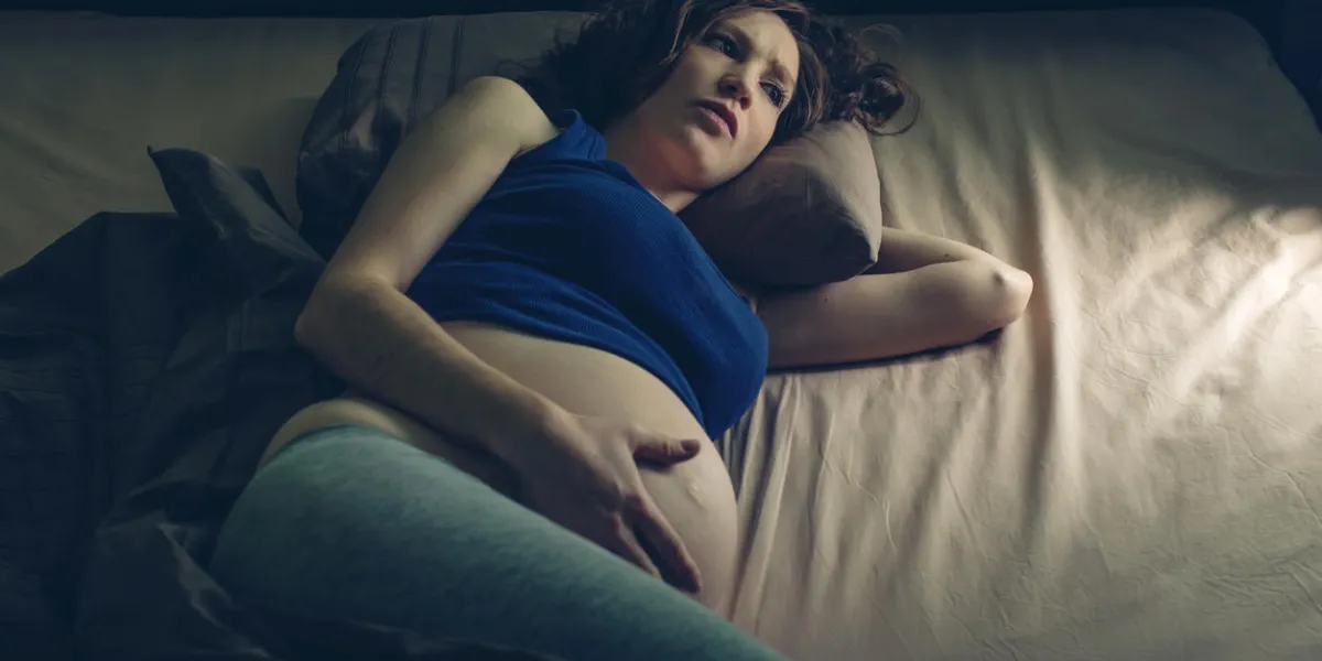 pregnant woman feeling pain in her belly lying in bed with insomnia at night the concept of pregnancy and health
