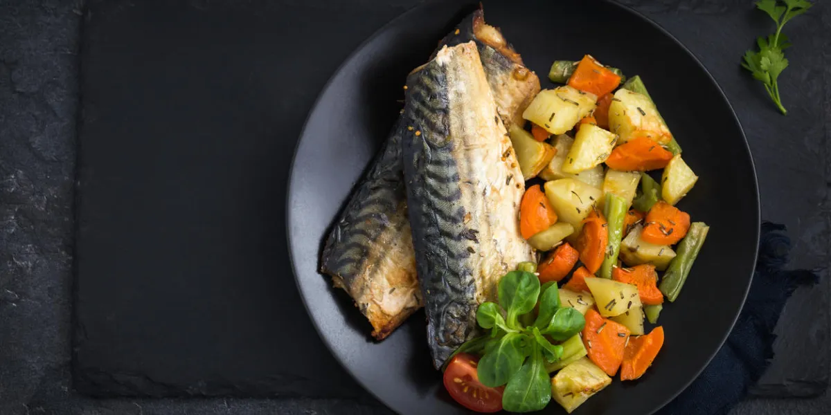 roasted mackerel and vegetables, dark background, top view