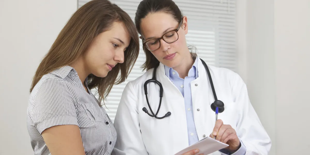 doctor showing notes to young patient