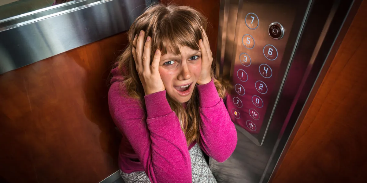 shocked woman with claustrophobia in the moving modern elevator