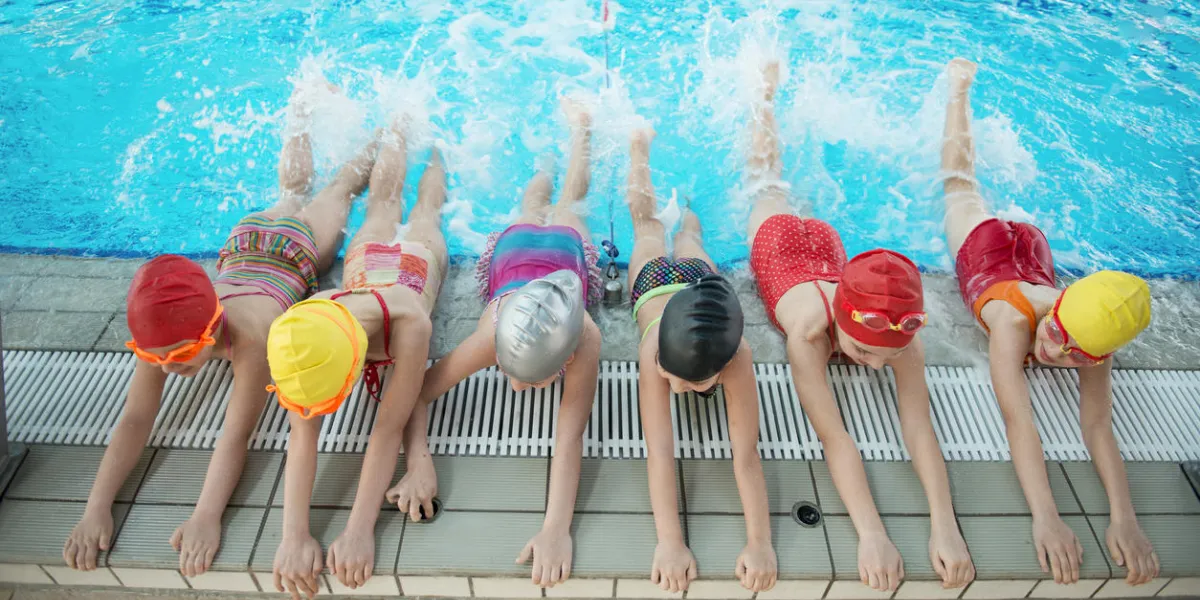 happy children kids group at swimming pool class learning to swim