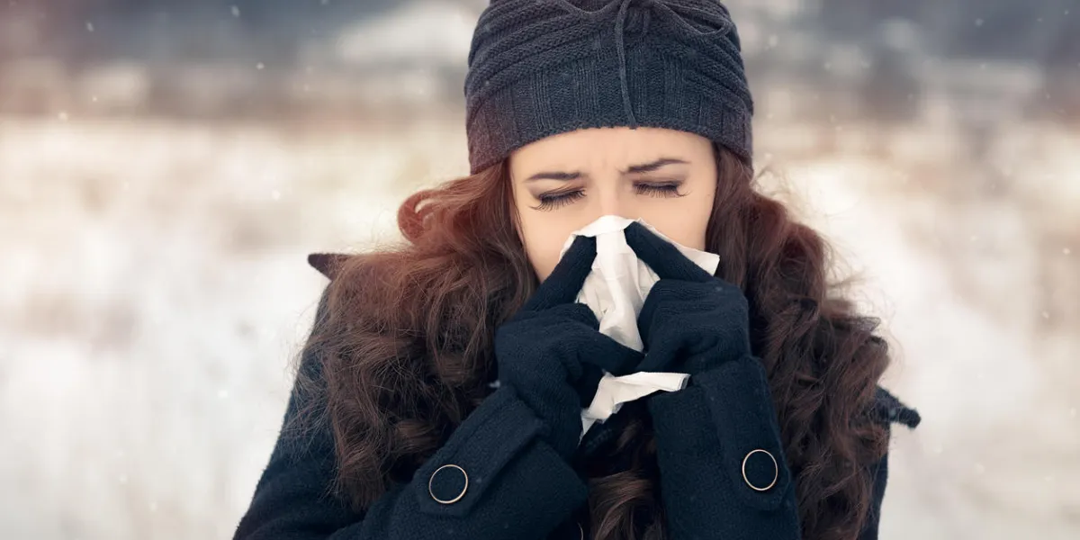 suffering ill girl with flue being cold holding paper napkin in wintertime