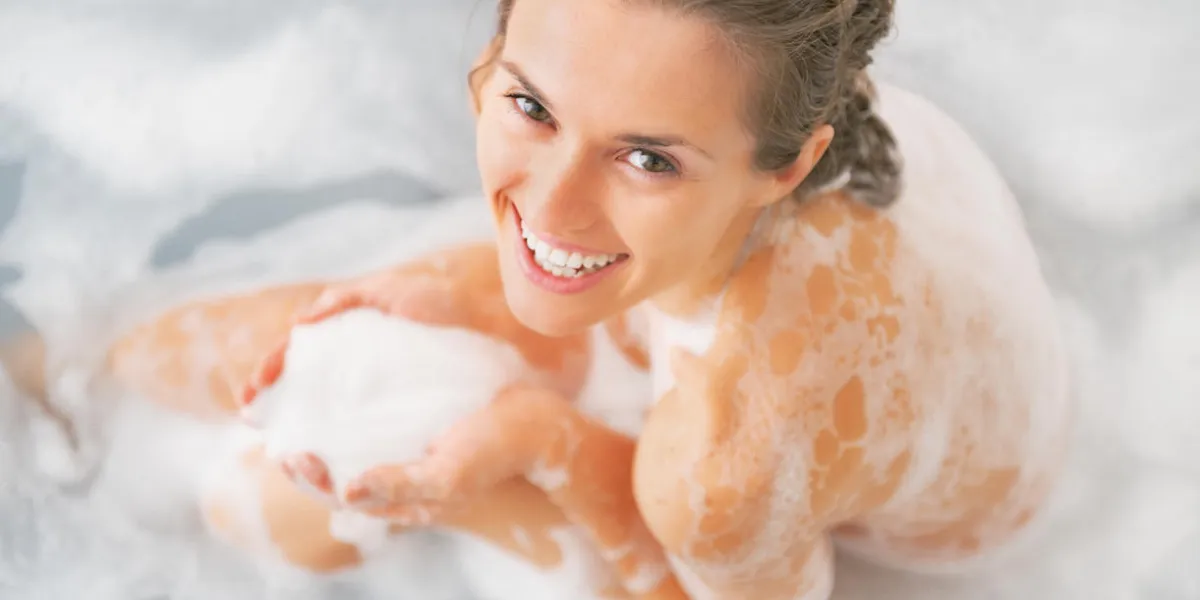 souriante jeune femme jouant avec de la mousse dans la baignoire