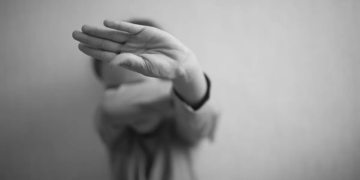 a little girl protects herself with her palm and covers her face