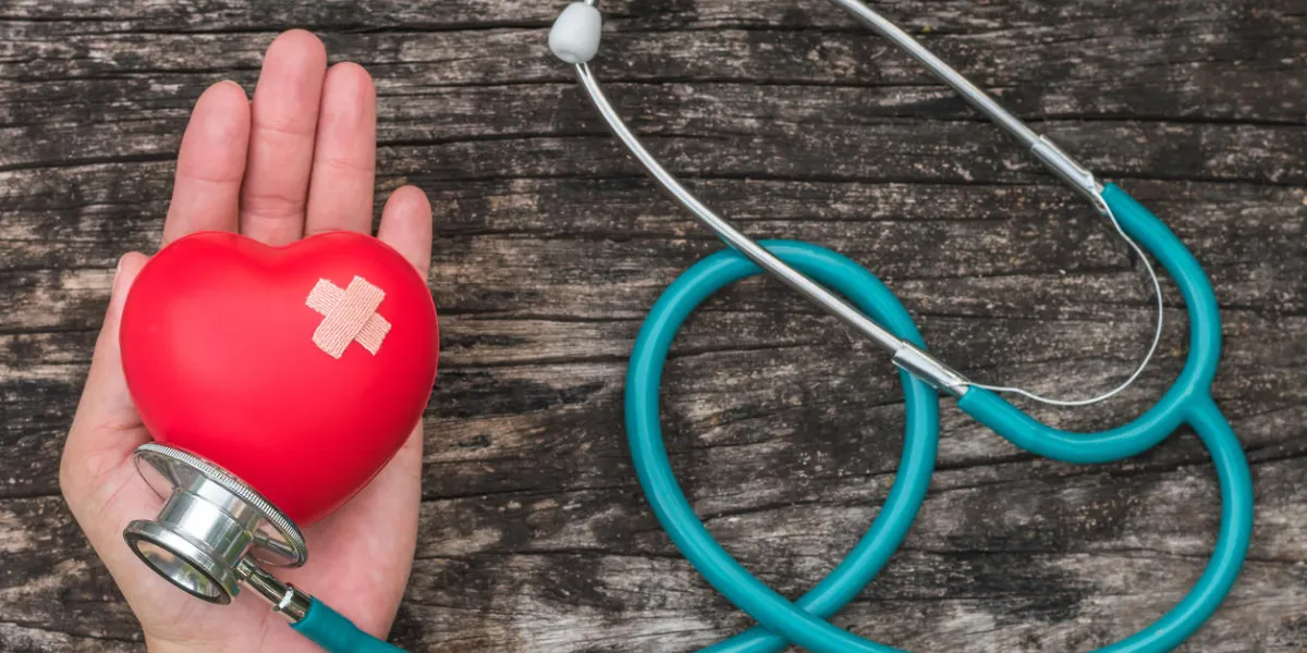 healthcare insurance and world heart health day concept with red heart on woman's hands support with medical doctor's stethoscope