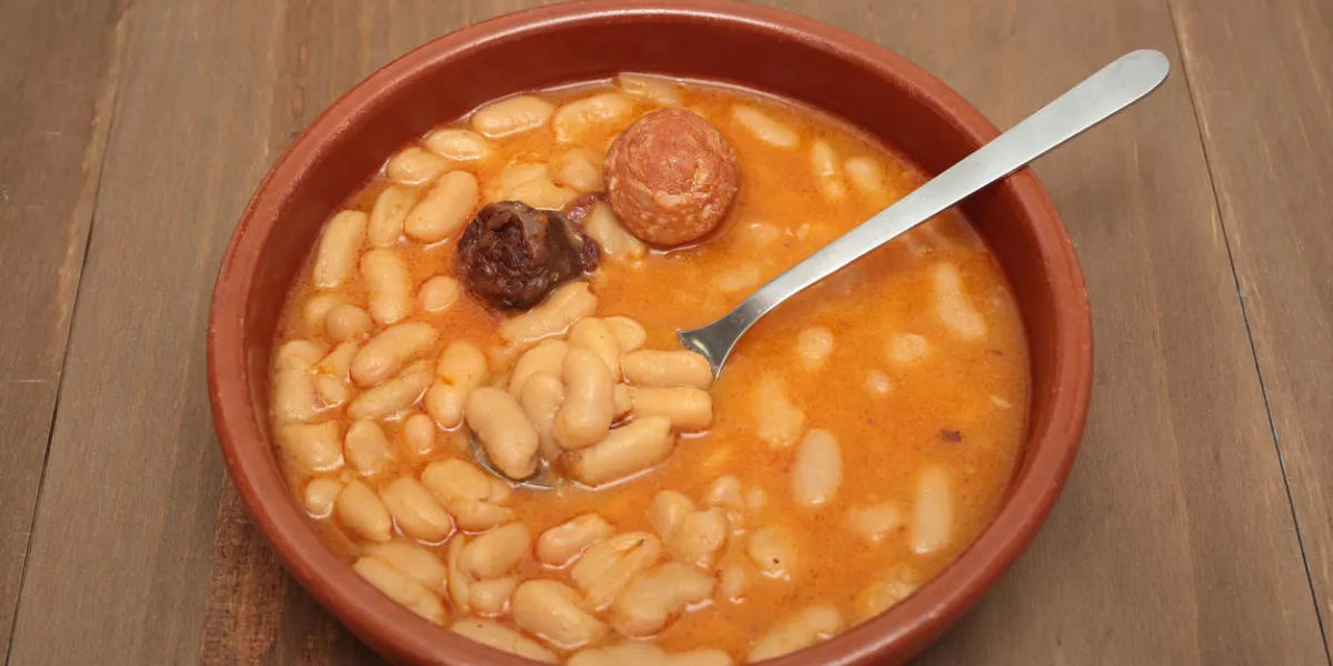 ragoût de haricots asturiens dans un pot en argile sur un fond de vieux bois ragoût de haricots asturiens dans un pot en argile sur un fond de vieux bois