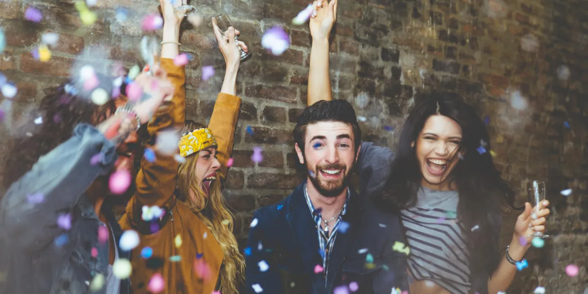 groupe de quatre amis rire à haute voix en plein air, partage de bonne humeur et faire la fête en plein air avec champagne et confettis