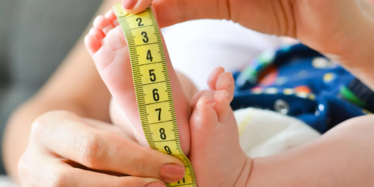 mother measuring tiny baby foot with a meter mother measuring tiny baby foot with a meter