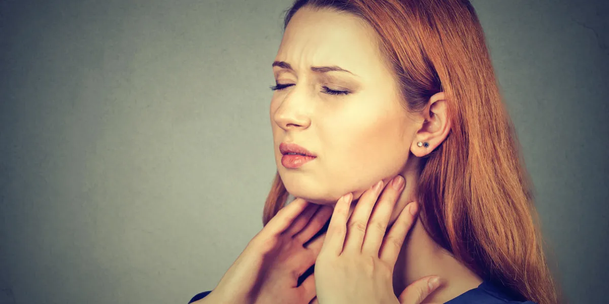 closeup girl with sore throat touching her neck sick young woman having pain in her throat isolated on gray wall background closeup girl with sore throat touching her neck sick young woman having pain in her throat isolated on gray wall background