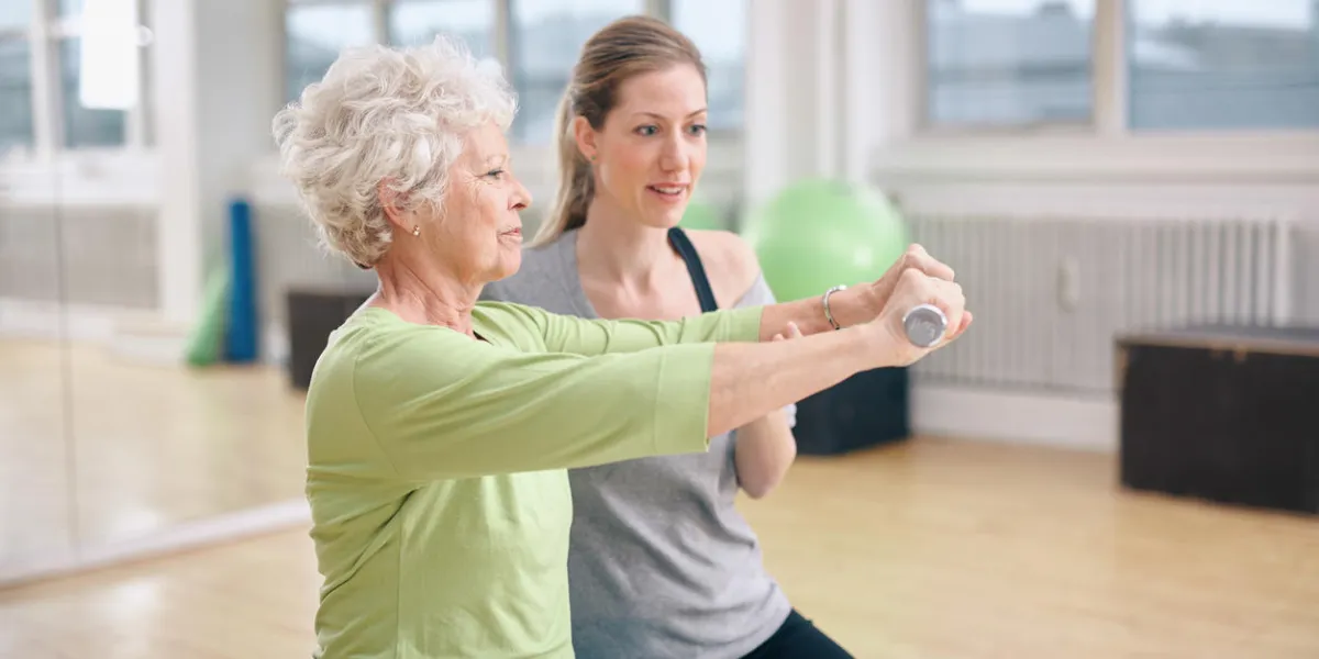 femme âgée, être, assisté, par, instructeur, dans, soulever, haltères, à, gymnase femme aînée, entraîner, dans, les, gymnase, à, a, personnel, entraîneur, à, rehab femme âgée, être, assisté, par, instructeur, dans, soulever, haltères, à, gymnase femme aînée, entraîner, dans, les, gymnase, à, a, personnel, entraîneur, à, rehab