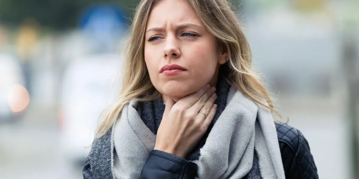 shot of illness young woman with terrible throat pain walking to the street