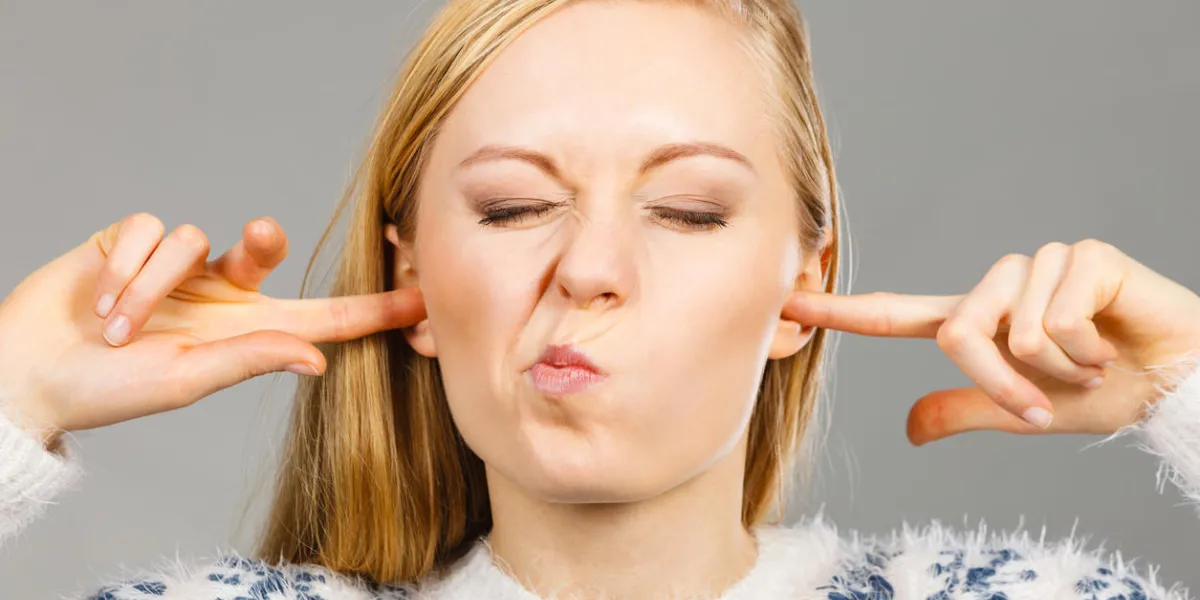 hearing problems concept young blonde woman covering ears with her fingers making funny face