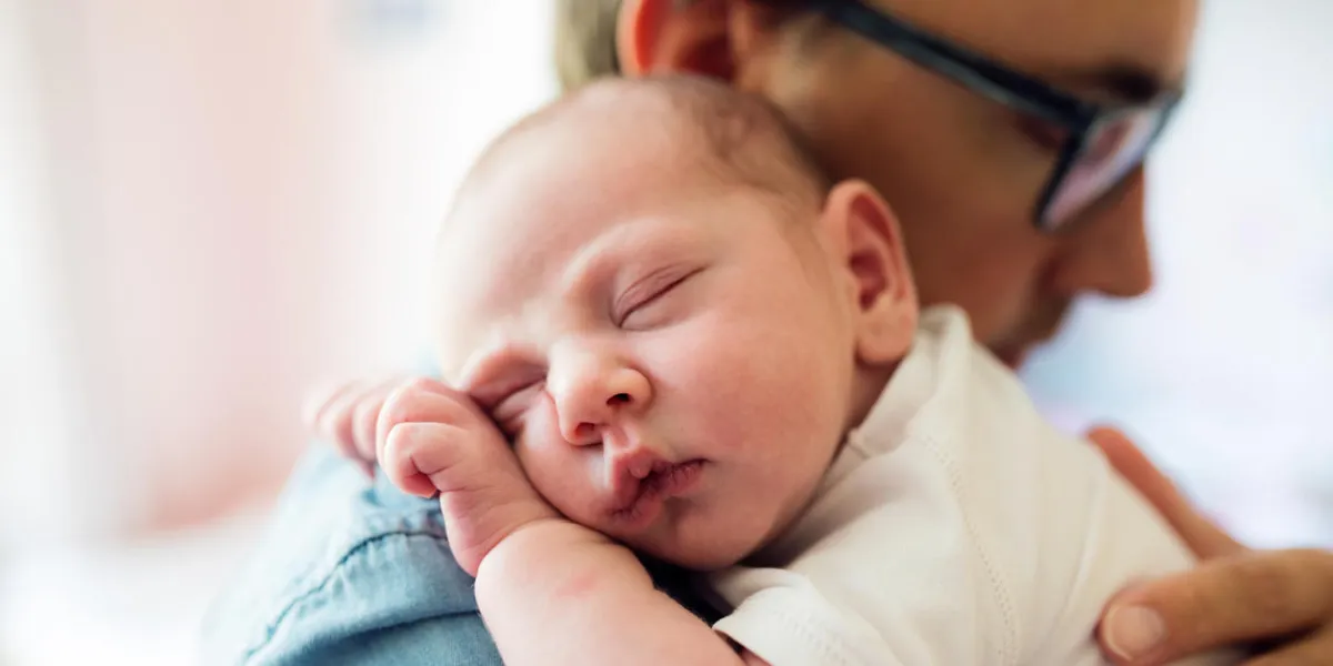 close up of young father holding his newborn baby son in his arms