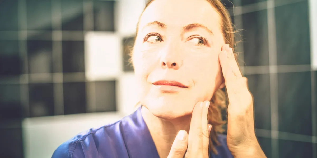 femme mature mettant la crème sur son visage, gros plan, copie espace
