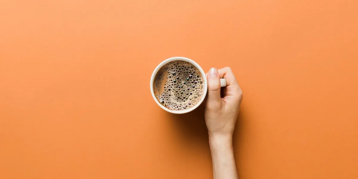 minimalistic style woman hand holding a cup of coffee on colored background flat lay, top view cappuccino cup empty place for text, copy space coffee addiction top view, flat lay