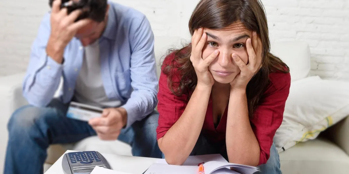 jeune couple inquiet à la maison dans le stress assis au salon canapé comptable dette factures bancaires papiers dépenses et paiements sentiment désespéré dans mauvaise situation financière
