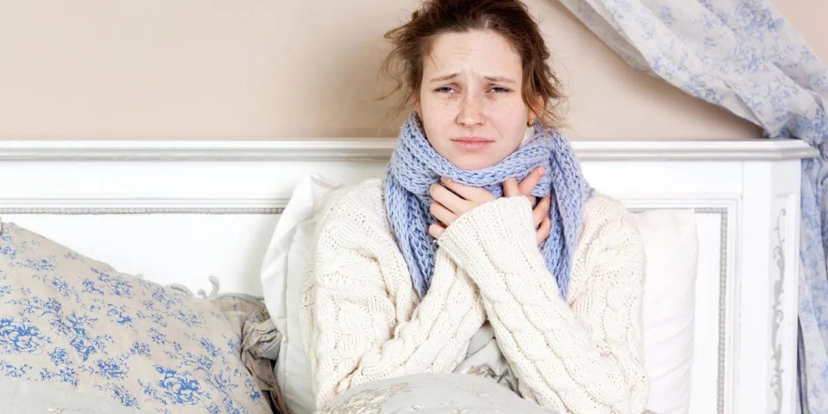 sick woman with terrible sore throat closeup image of young woman with red nose in bed with thick scarf and touching her neck and head feeling pain sick woman with terrible sore throat closeup image of young woman with red nose in bed with thick scarf and touching her neck and head feeling pain