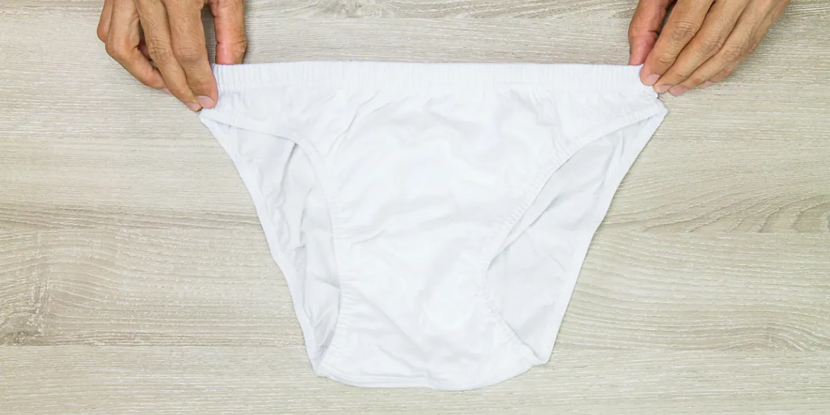 hands holding men white underwear on wooden background hands holding men white underwear on wooden background