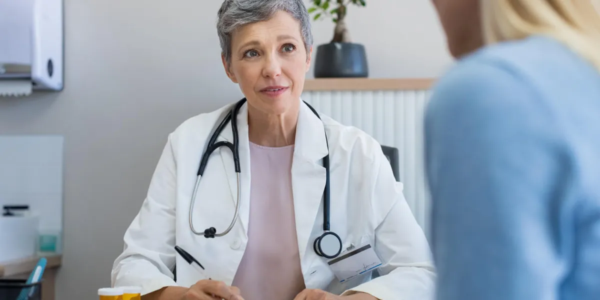 senior female doctor listening to patient explaining her painful in her office mature woman doctor consulting patient in hospital room doctor and patient discussing health issue in office