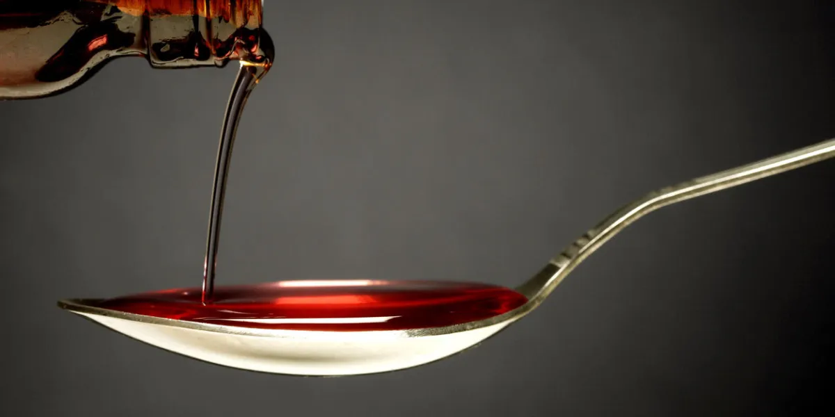 pouring cough syrup into a spoon pouring cough syrup into a spoon