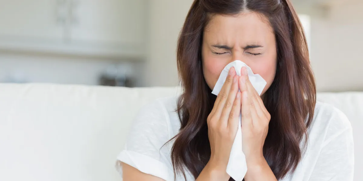 brunette sneezing in a tissue in the living room