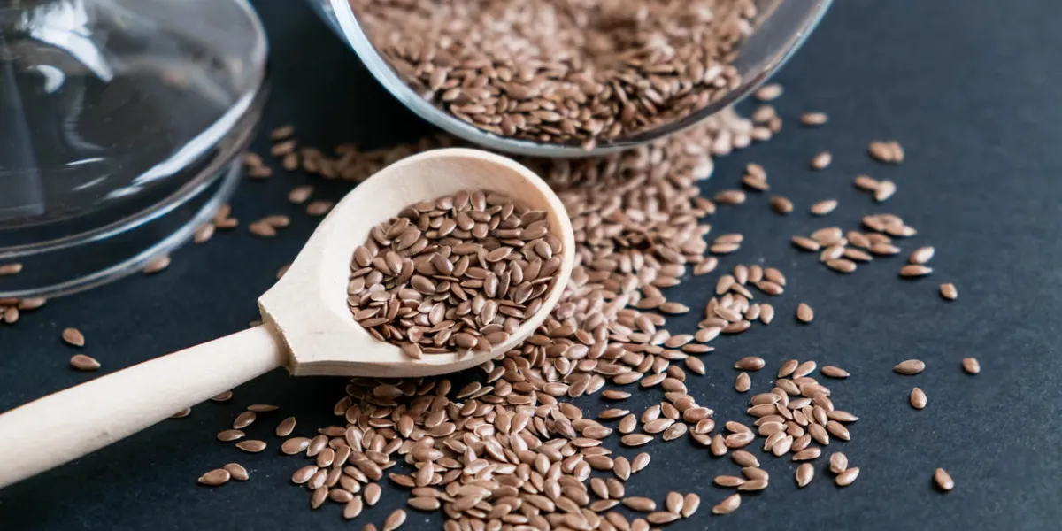 flax seeds in spoons over dark background natural light selective focus close up on a black background top view, flat lay copy space