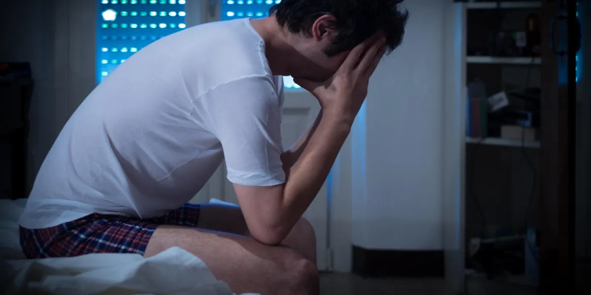 sad and lonely man seated on his bed sad and lonely man seated on his bed