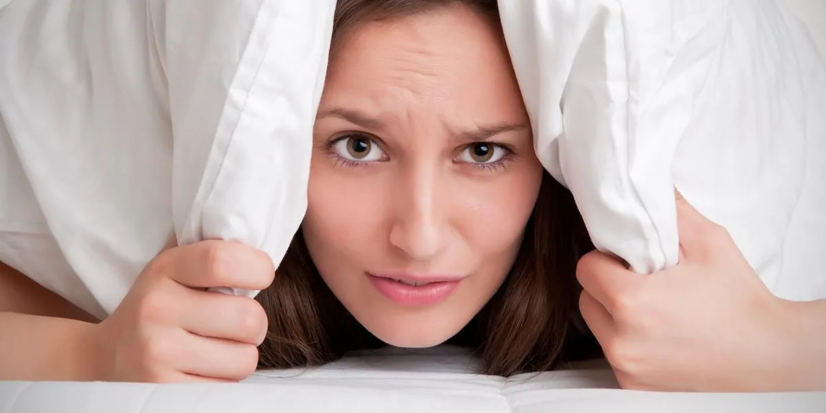 femme avec un oreiller sur la tête, ne voulant pas sortir du lit, isolé en blanc femme avec un oreiller sur la tête, ne voulant pas sortir du lit, isolé en blanc
