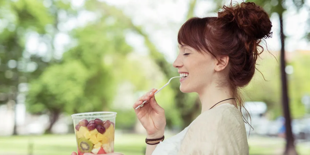jeune femme apprécie une salade de fruits frais