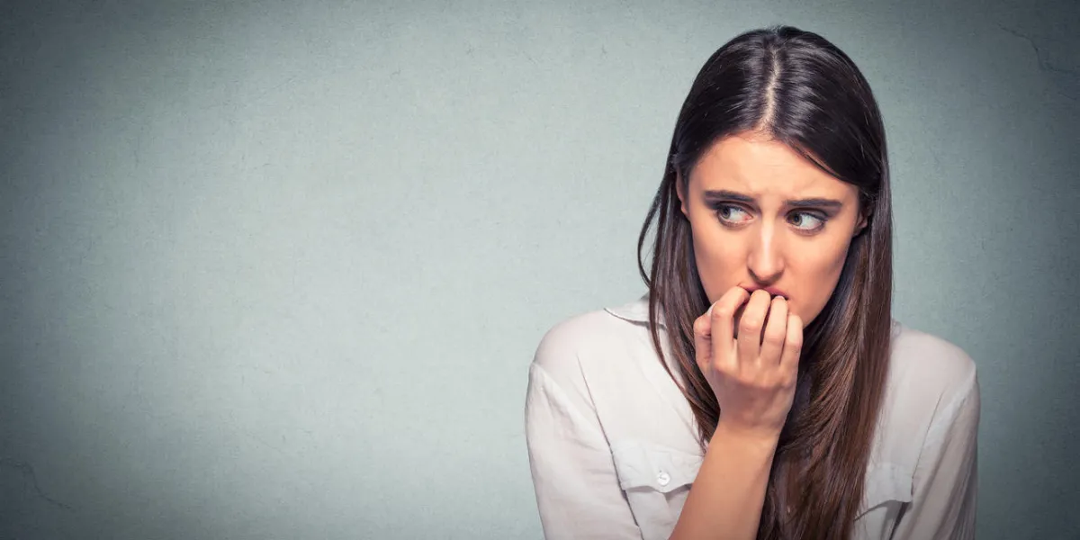 jeune femme nerveuse hésitante se ronger les ongles envie de quelque chose ou anxieux, isolé sur fond de mur gris avec espace copie négatif émotions humaines expression faciale sentiment