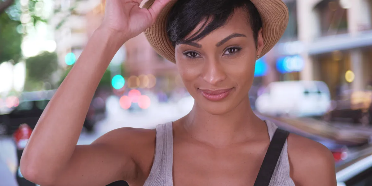 heureuse femme noire souriante tenant un chapeau sur la rue de la ville de san francisco