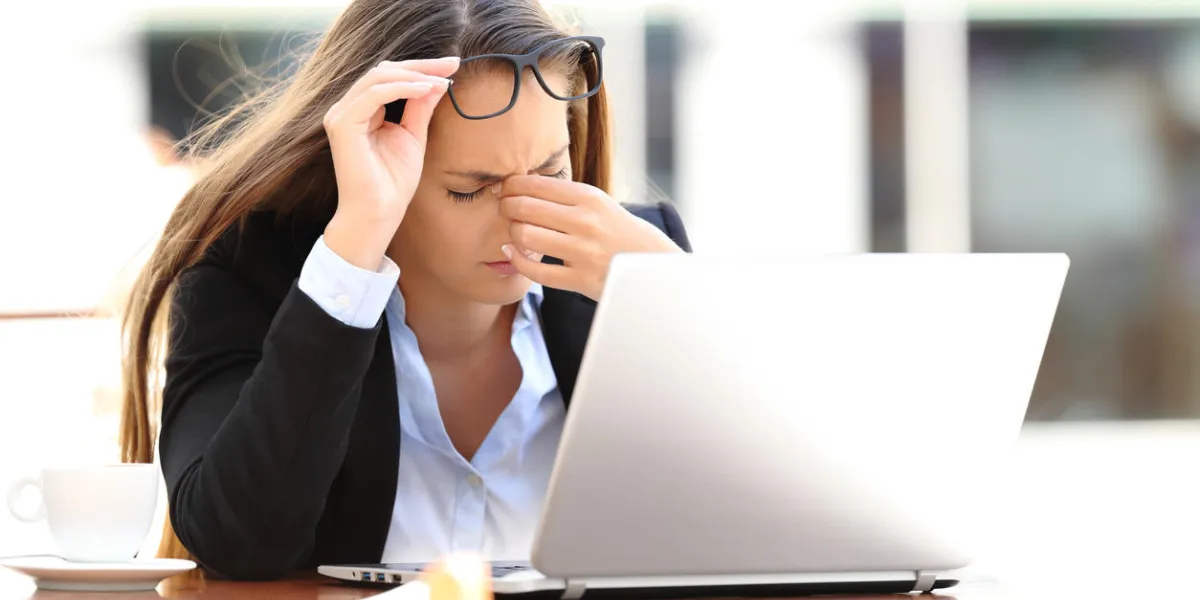 tired worker woman suffering eyestrain working on line sitting in a coffee shop