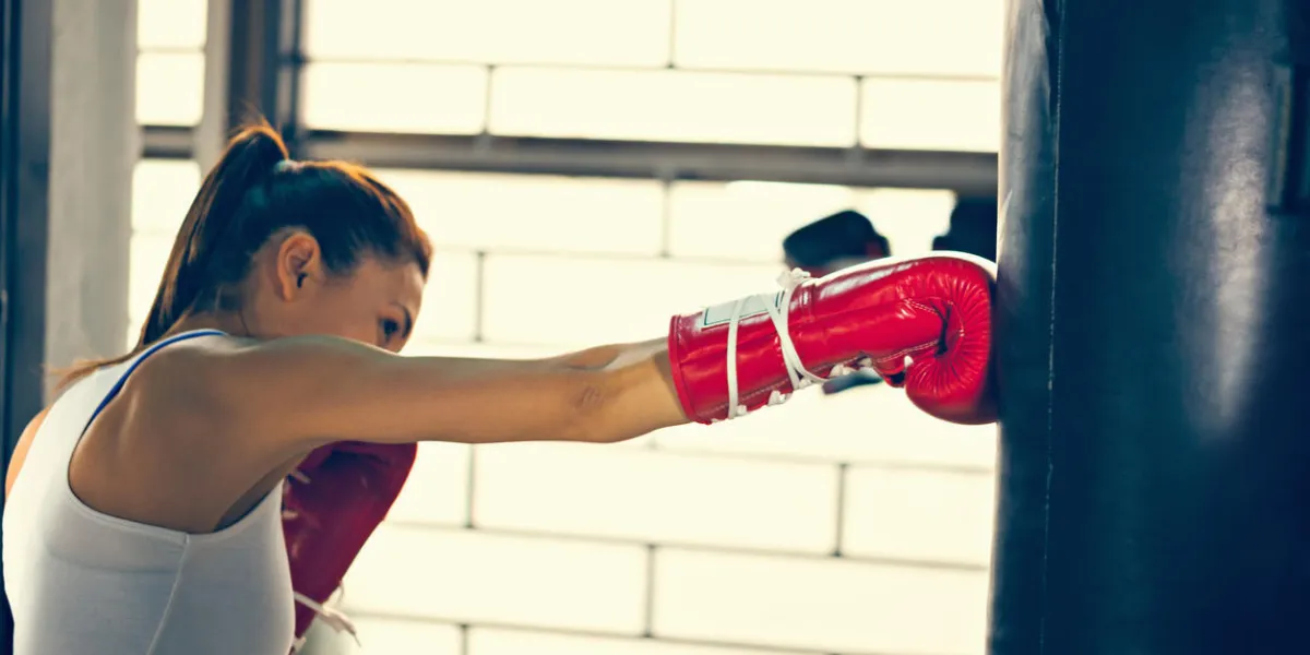 femme séduisante poinçonnage d'un sac avec des gants de boxe sur