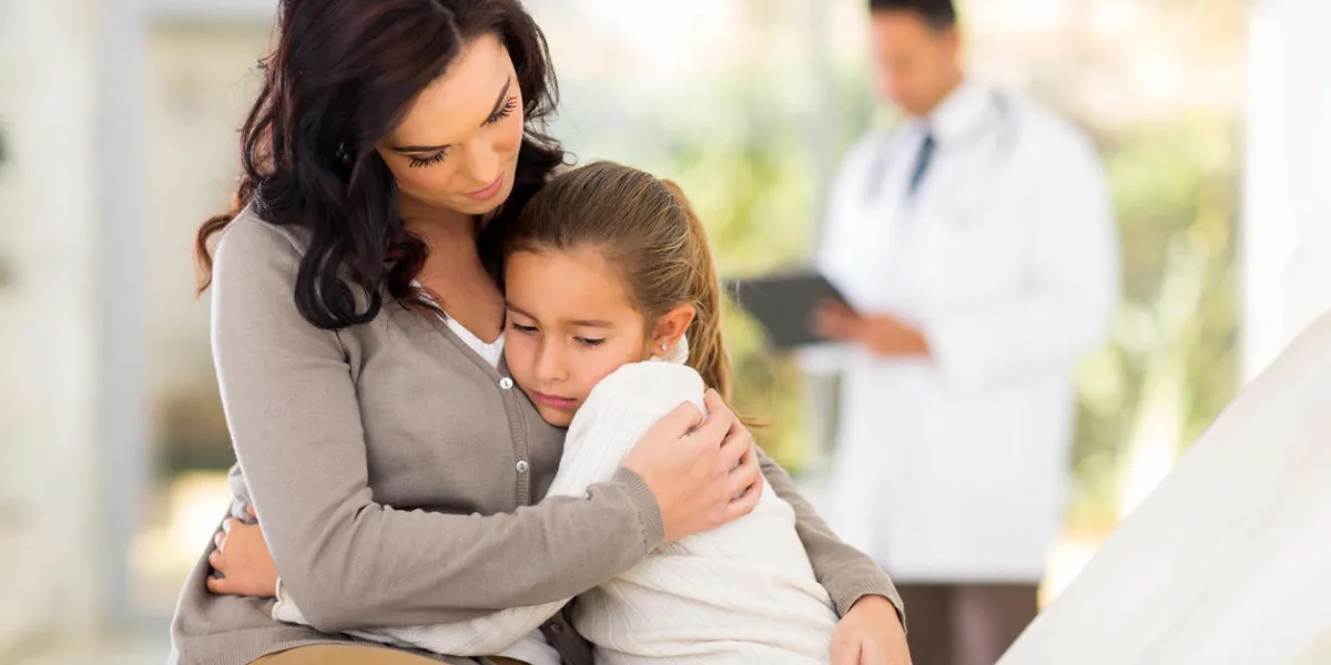 sad young woman and her sick daughter waiting for checkup in doctor's room
