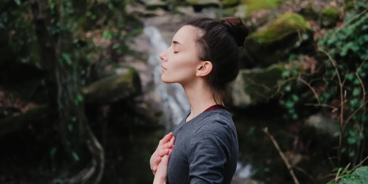 young woman practicing breathing yoga pranayama outdoors in moss forest on background of waterfall unity with nature concept young woman practicing breathing yoga pranayama outdoors in moss forest on background of waterfall unity with nature concept