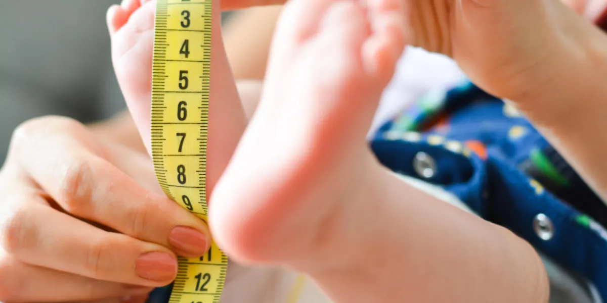 mother measuring tiny baby foot with a meter