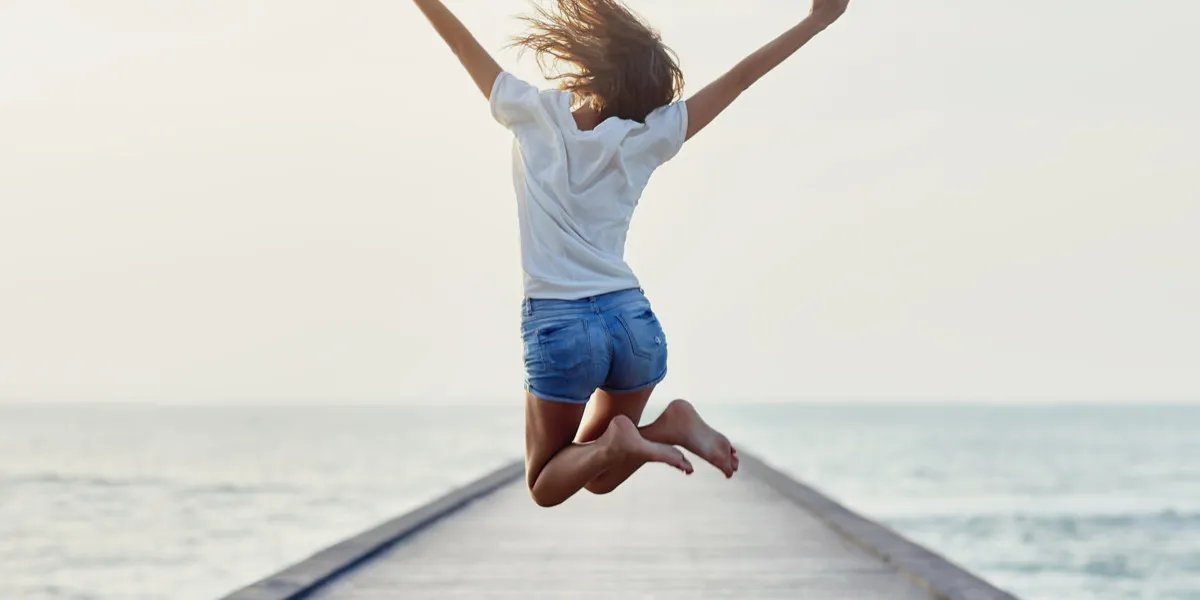 back view of jumping girl on the pier freedom concept back view of jumping girl on the pier freedom concept