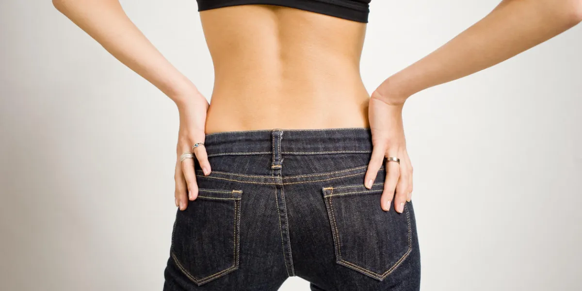 a slim, young japanese woman poses with her hands of her hips (from behind) a slim, young japanese woman poses with her hands of her hips (from behind)