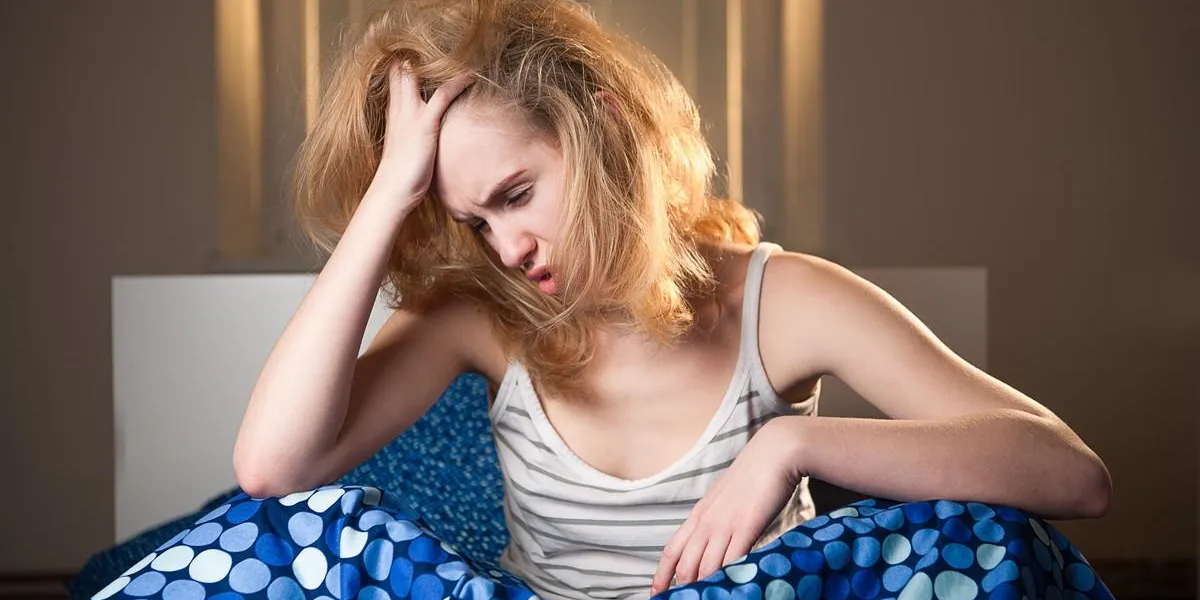 young caucasian woman in bed with headache and hangover