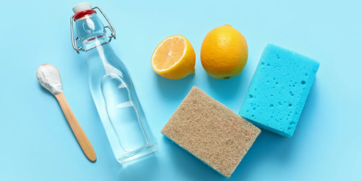 bottle of vinegar, baking soda, sponges and lemons on color background bottle of vinegar, baking soda, sponges and lemons on color background