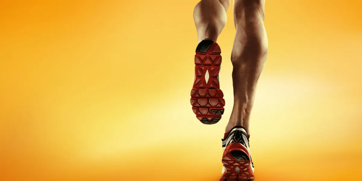 low angle view of male runners legs running down road wearing trainers