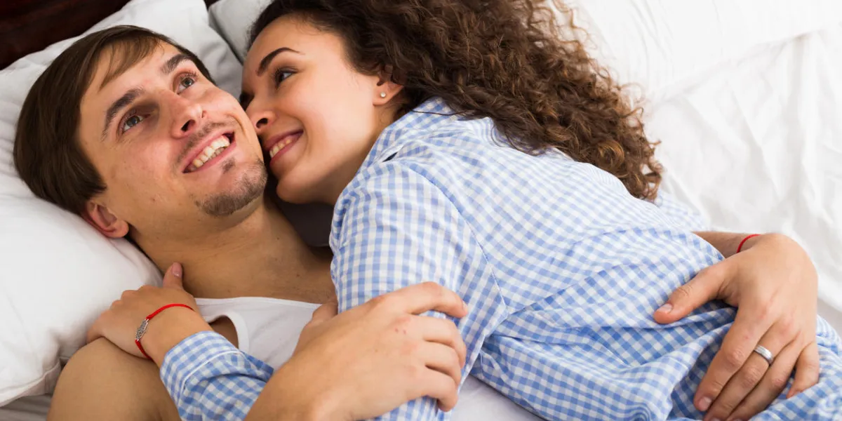 heterosexual couple in pygamas resting in family bed and smiling heterosexual couple in pygamas resting in family bed and smiling