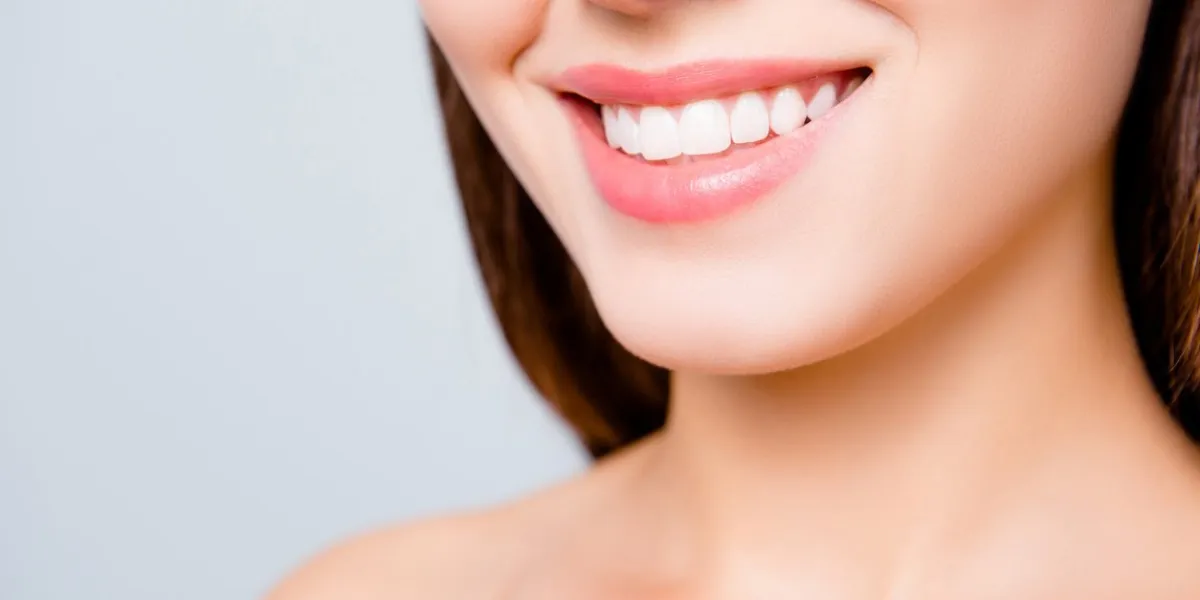 close up portrait of beautiful wide smile with whitening teeth of young fresh woman isolated over white background, dental care