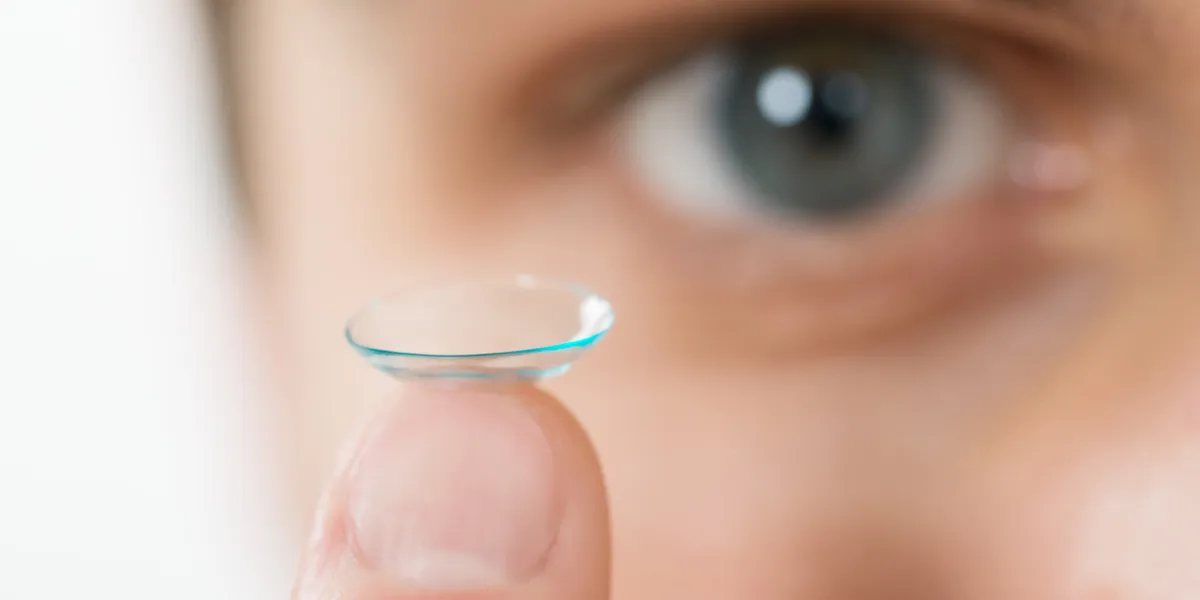 close-up of young man holding contact lens on finger close-up of young man holding contact lens on finger