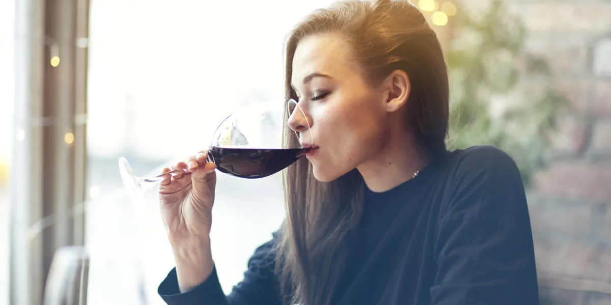 beautiful young woman drinking red wine with friends in cafe, portrait with wine glass near window vocation holidays evening concept