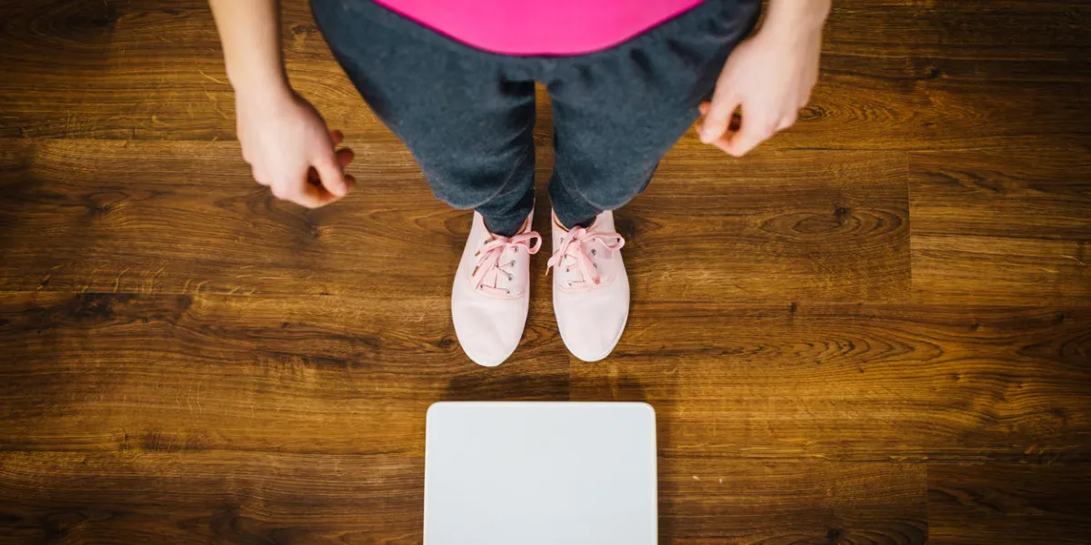 top view of woman feet wearing pink sneakers on bathroom weight scale fit, dieting, fat loss concept