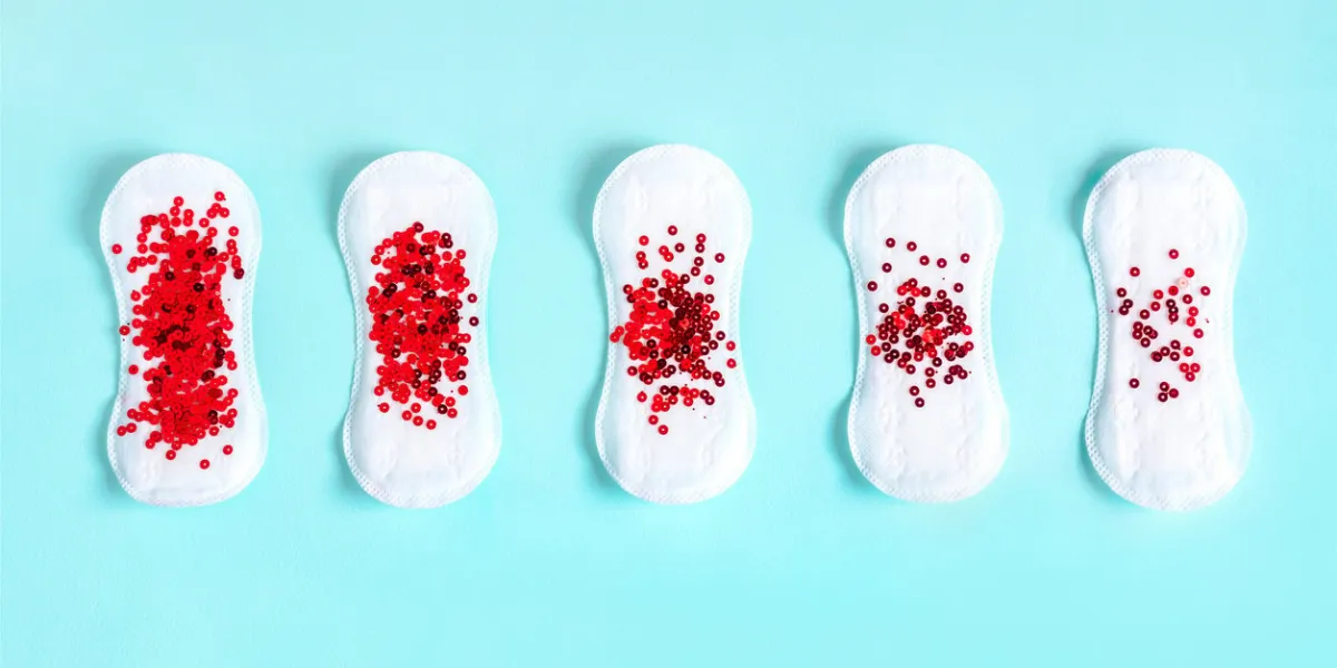 two menstrual pads with red glitter on blue colored background minimalist still life photography concept